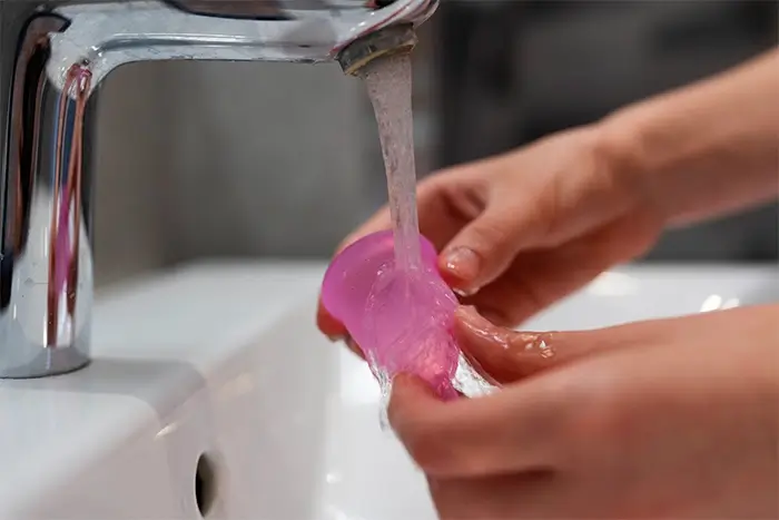 Mulher lavando o coletor menstrual na torneira